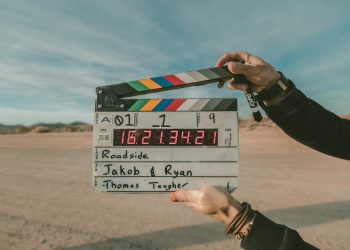 A person holds a film clapperboard outdoors in a desert landscape. The board displays the words “Roadside,” “Jakob & Ryan,” and “Thomas Tangher,” with a digital timecode and other scene details visible. | IFVOD-TV.com