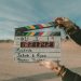 A person holds a film clapperboard outdoors in a desert landscape. The board displays the words “Roadside,” “Jakob & Ryan,” and “Thomas Tangher,” with a digital timecode and other scene details visible. | IFVOD-TV.com